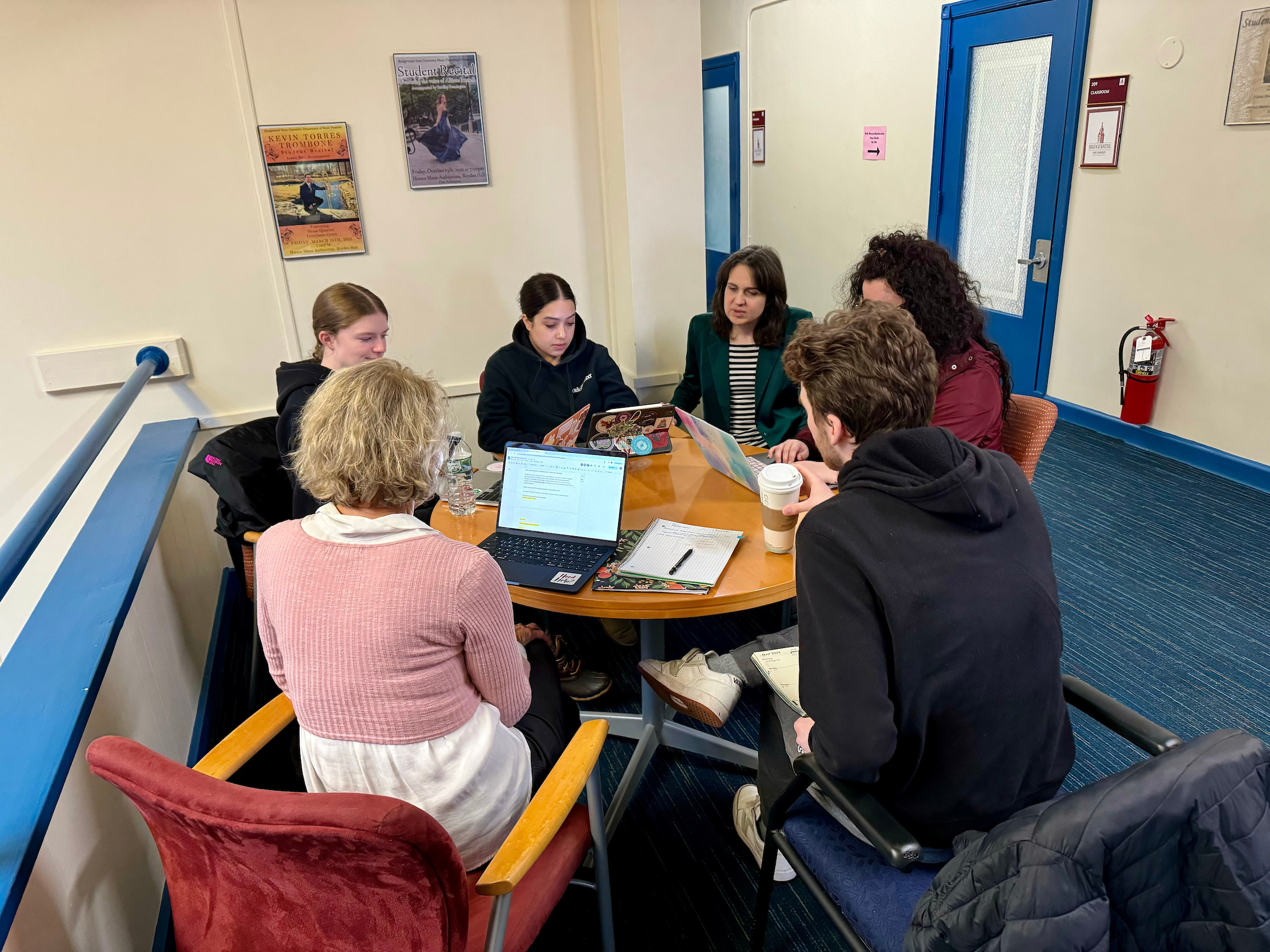 A professor and six students sitting working together at a round table