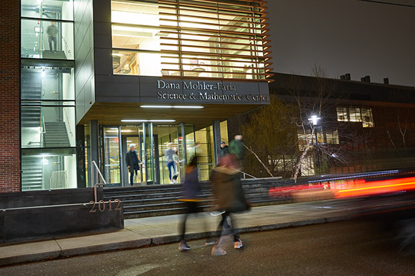 exterior photo of BSU's Dana Mohler-Faria Math and Science Center in the evening with people inside and outside of building