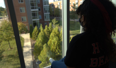 A student sits and looks out window on campus