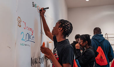 A charter school student makes a design on paper hung on a wall.