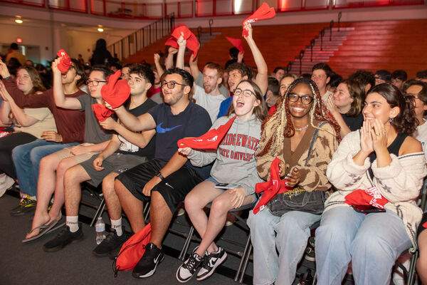 A crowd of students cheer and wave red towels at the Crimson Celebration