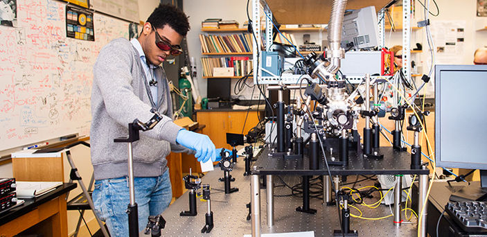A BSU student working with photonics equipment in BSU photonics lab