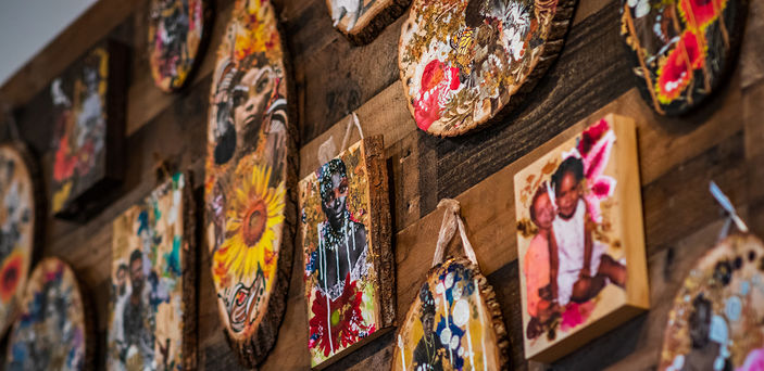 Portraits of people done on small wooden boards hang from the gallery wall.