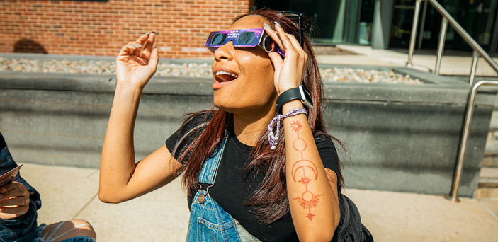 A student wearing glasses gazes at the eclipse.