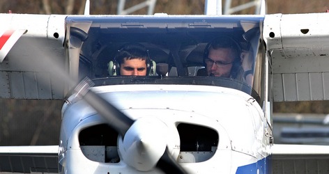 two people flying a plane with headphones on. One person is