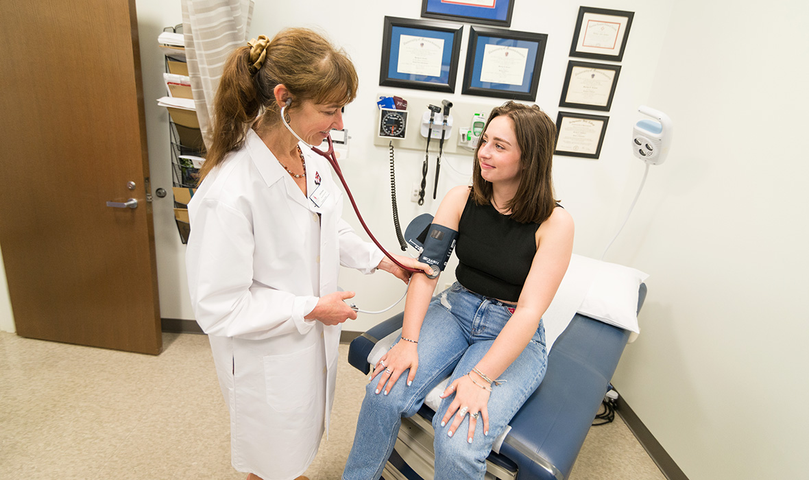 A wellness center doctor checks the blood pressure of a student in a Wellness Center appointment room
