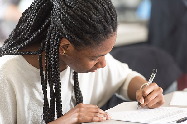 a student leans over a desk writing