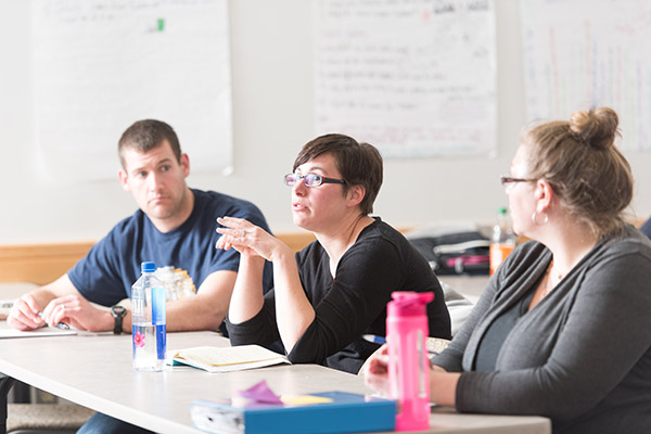 3 students in an education class, one speaking and the others listening