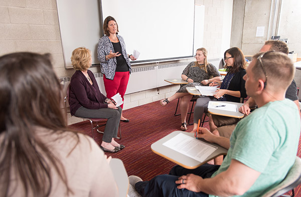 Dr. Katherine Bender teaching a small circle of students in desks
