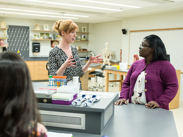 Professor Maria Armour talks with a student in biology lab