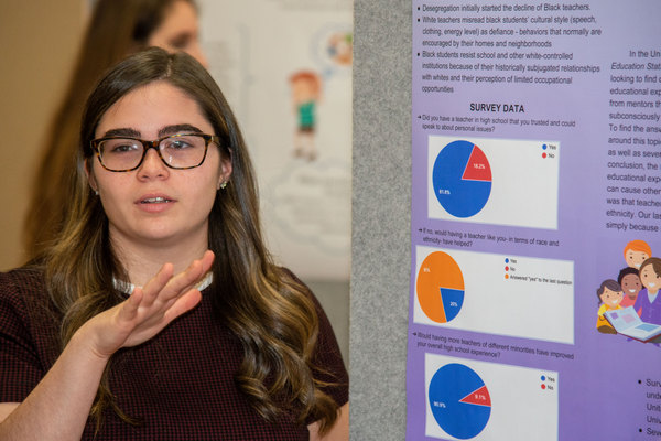 a female student giving a poster presentation on her research