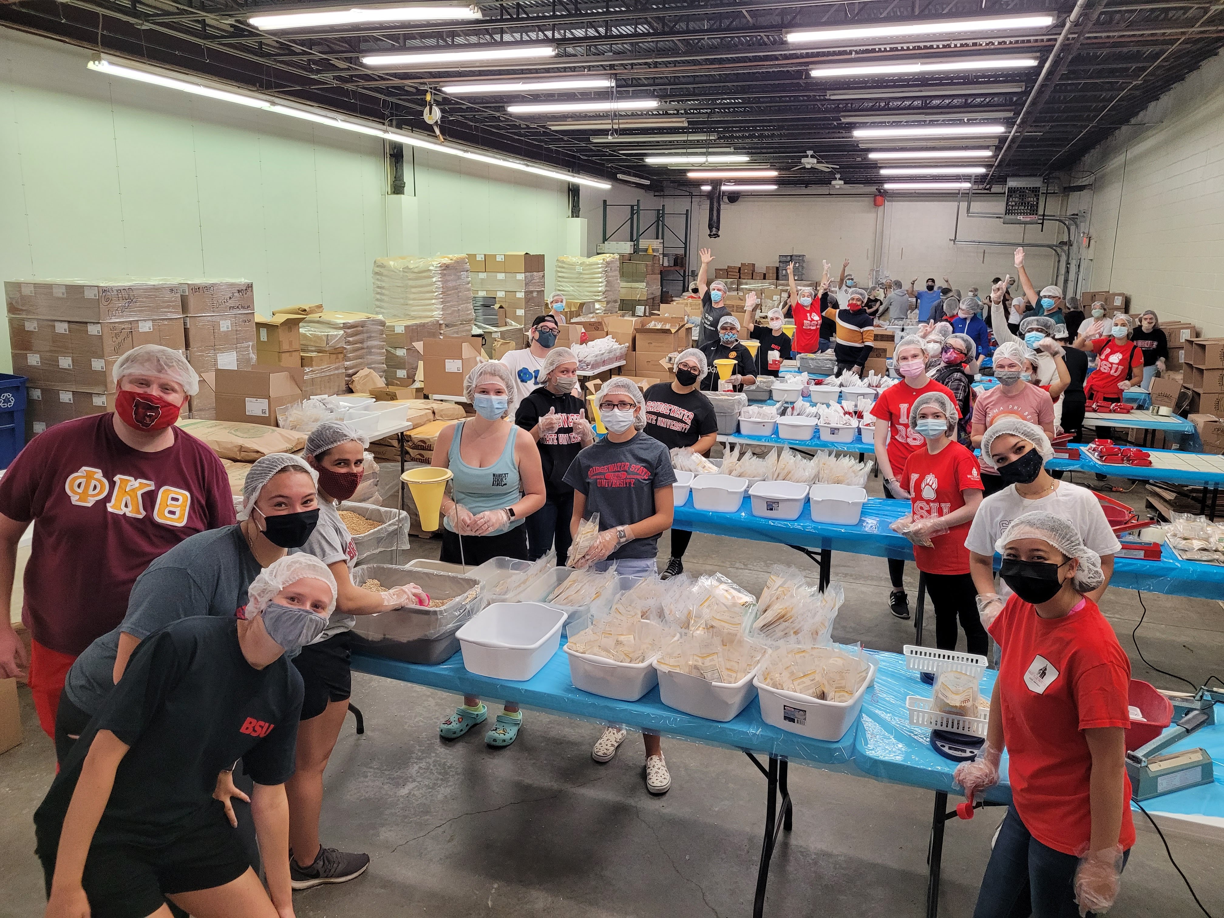 20210911_111248.jpg Photo of BSU student volunteers at End Hunger New England packing meals for folks experiencing homelessness. They are spaced out across 4 tables in groups, and are wearing masks, gloves and hairnets and looking at the camera