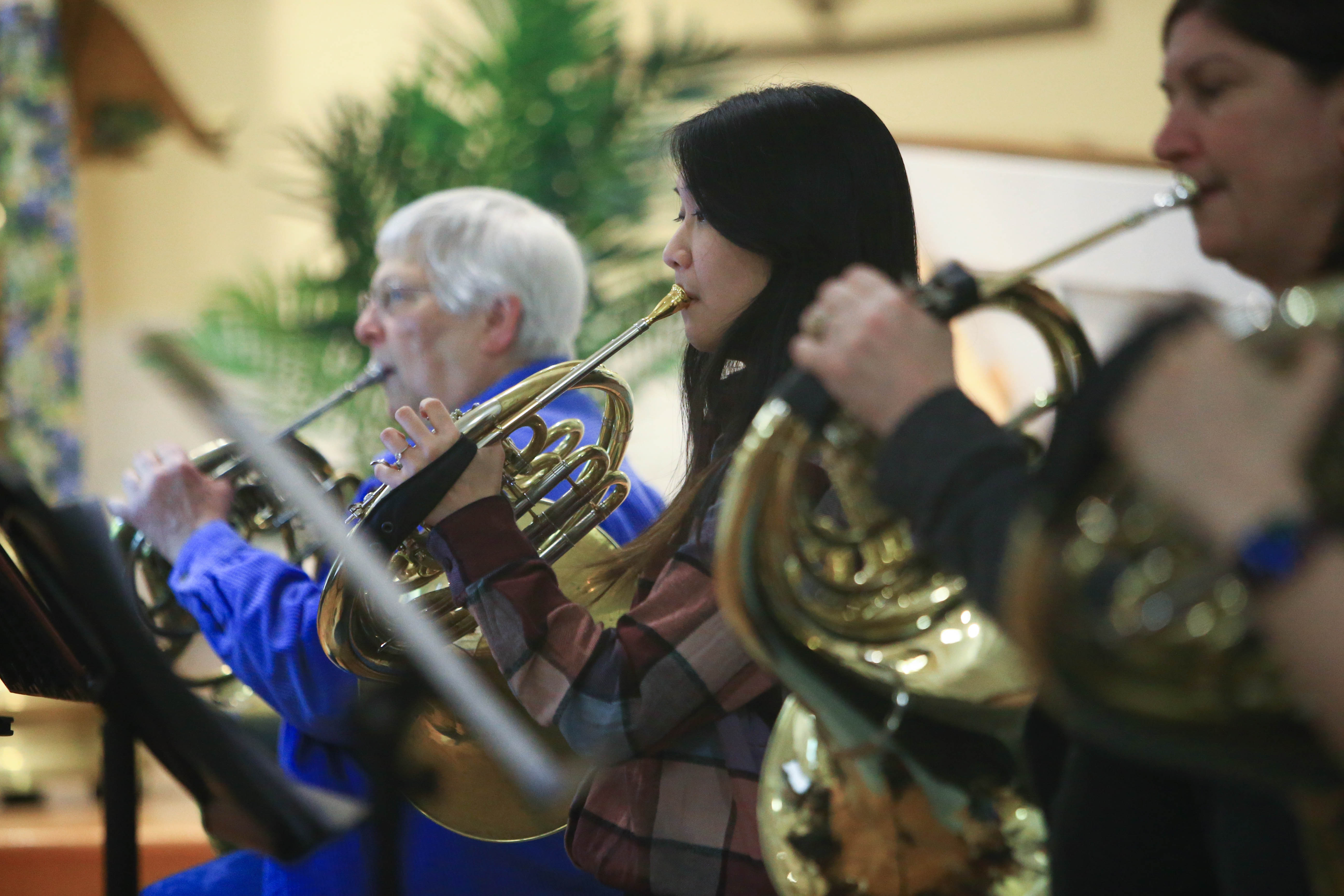 A student plays the French horn in a music ensemble