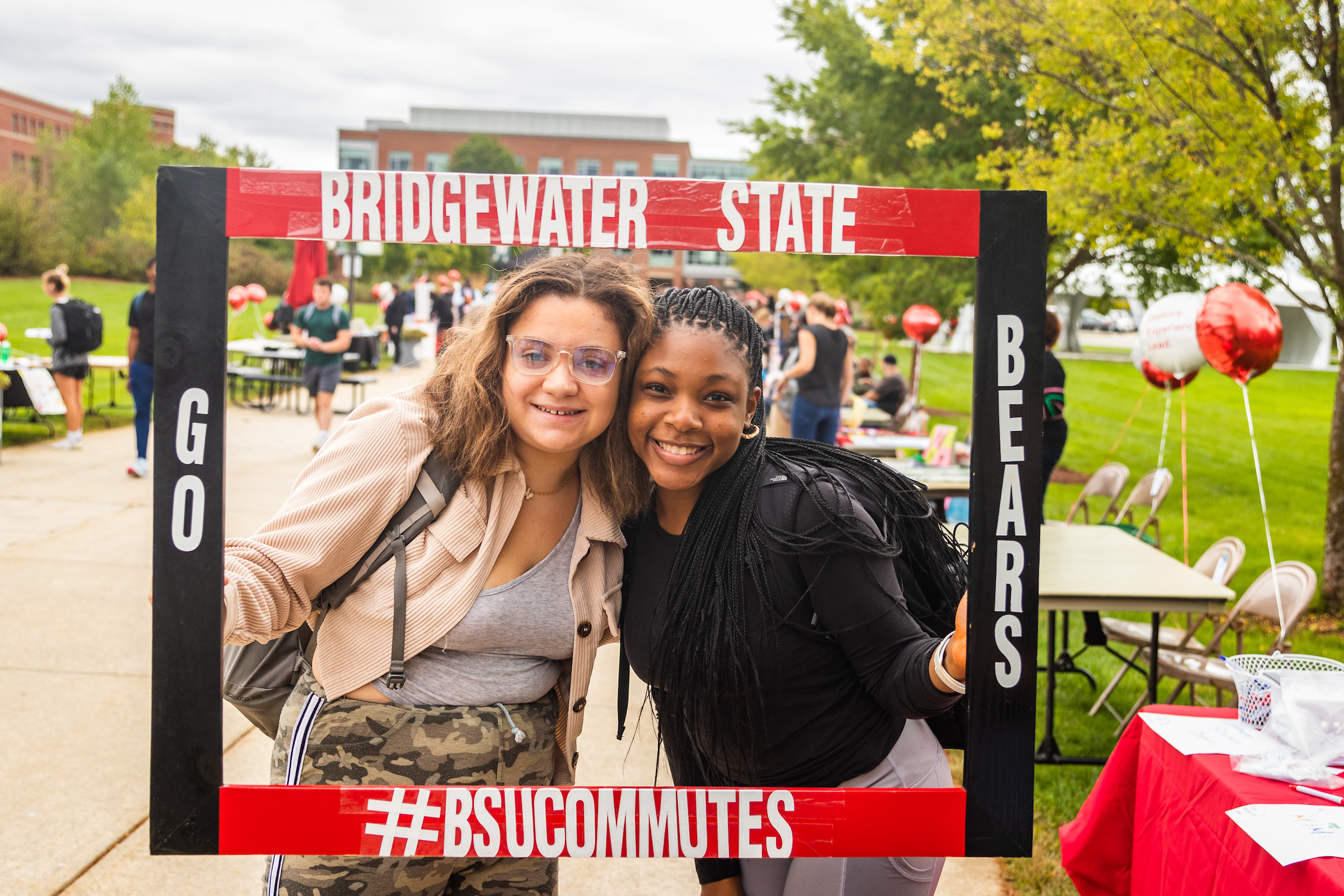 2 BSU smiling students holding and looking through a large BSU frame