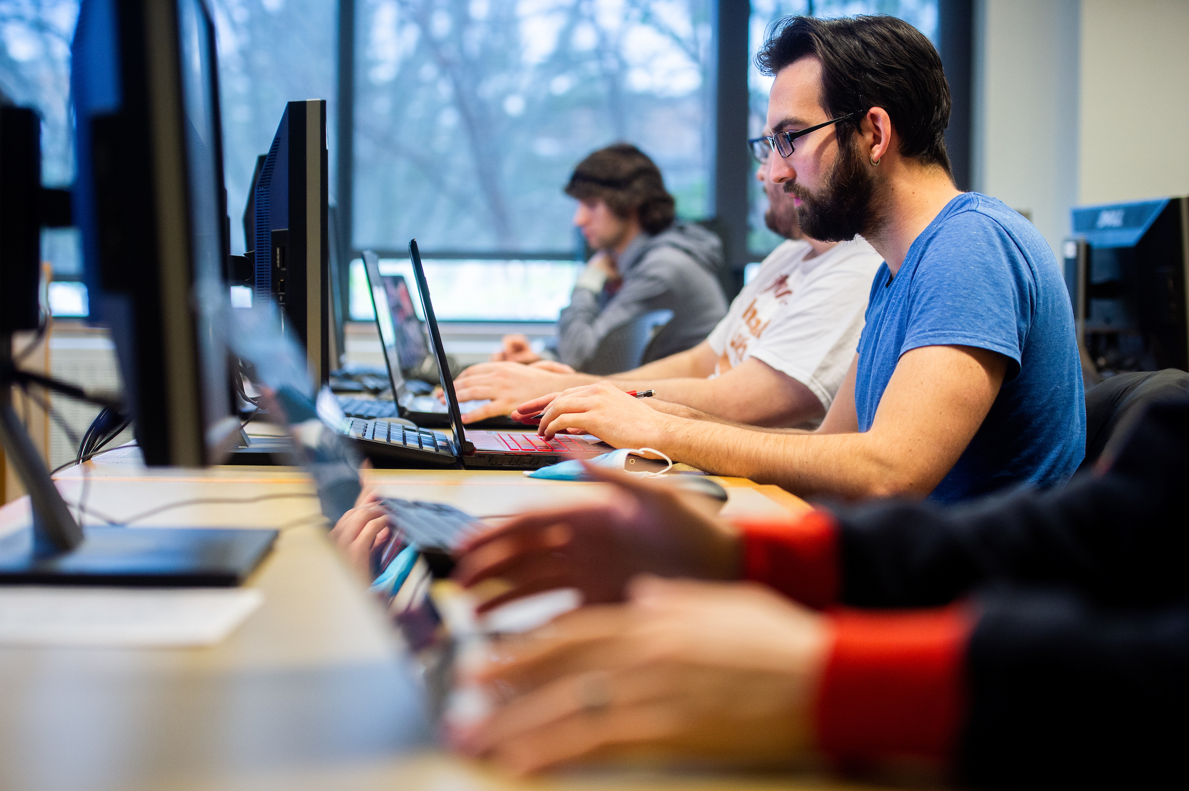 students sitting at a long table working on computers