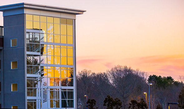 Sunset reflects off the glass windows of the parking garage on East Campus