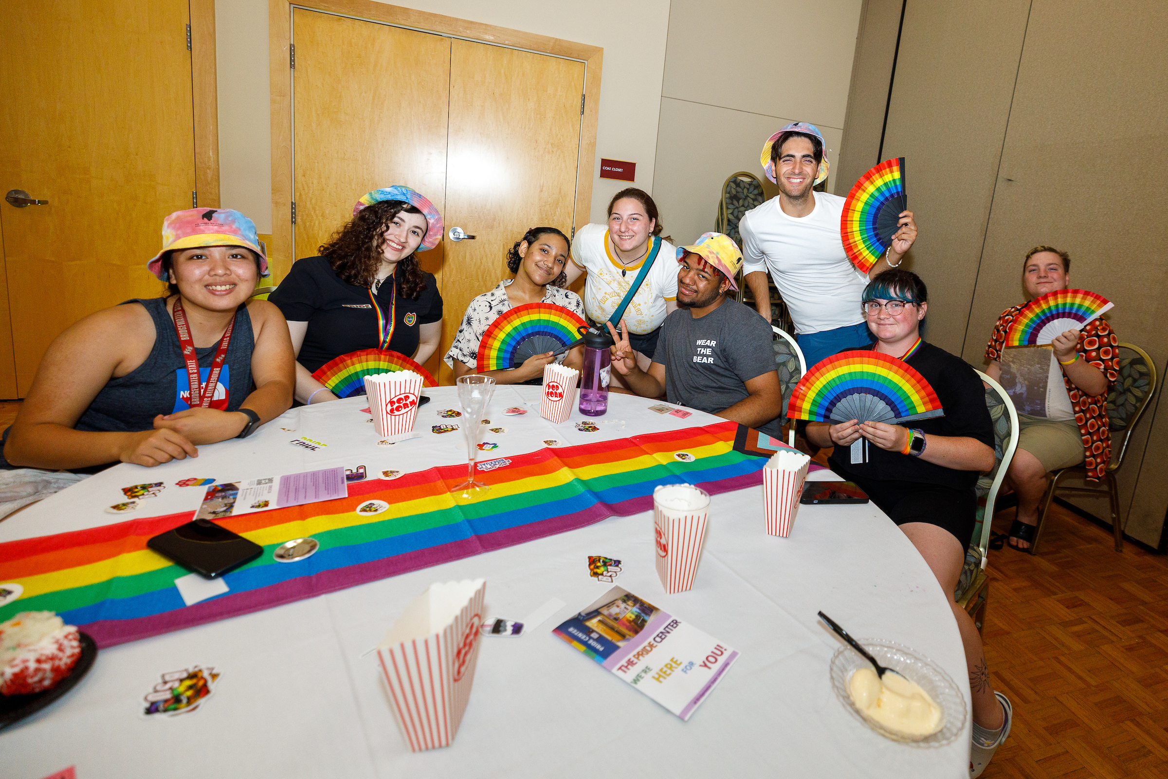 students holding rainbow fans sitting around a table decorated with a rainbow table runner