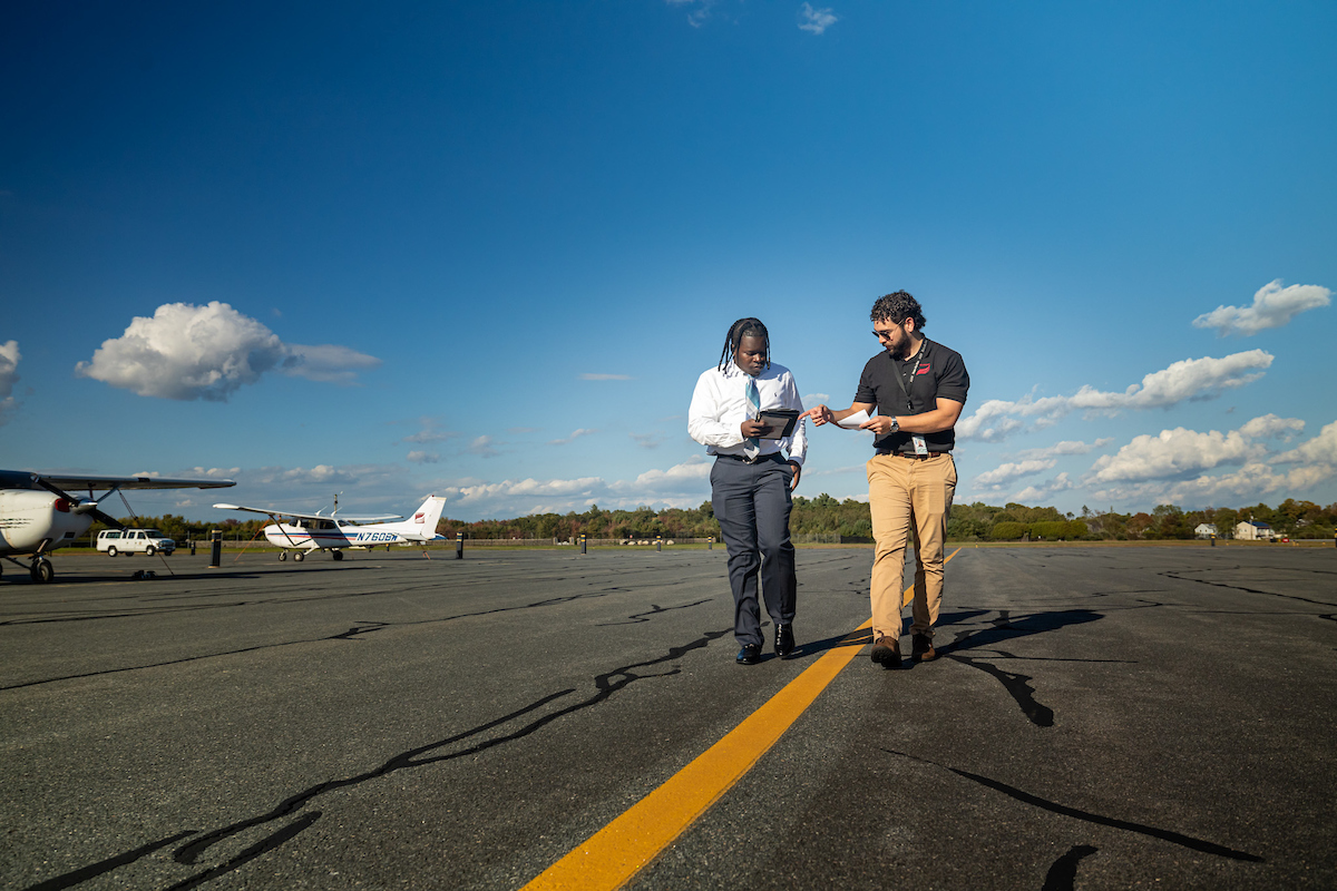 a BSU flight instructor talks with a BSU aviation student on the tarmac at the New Bedford airport