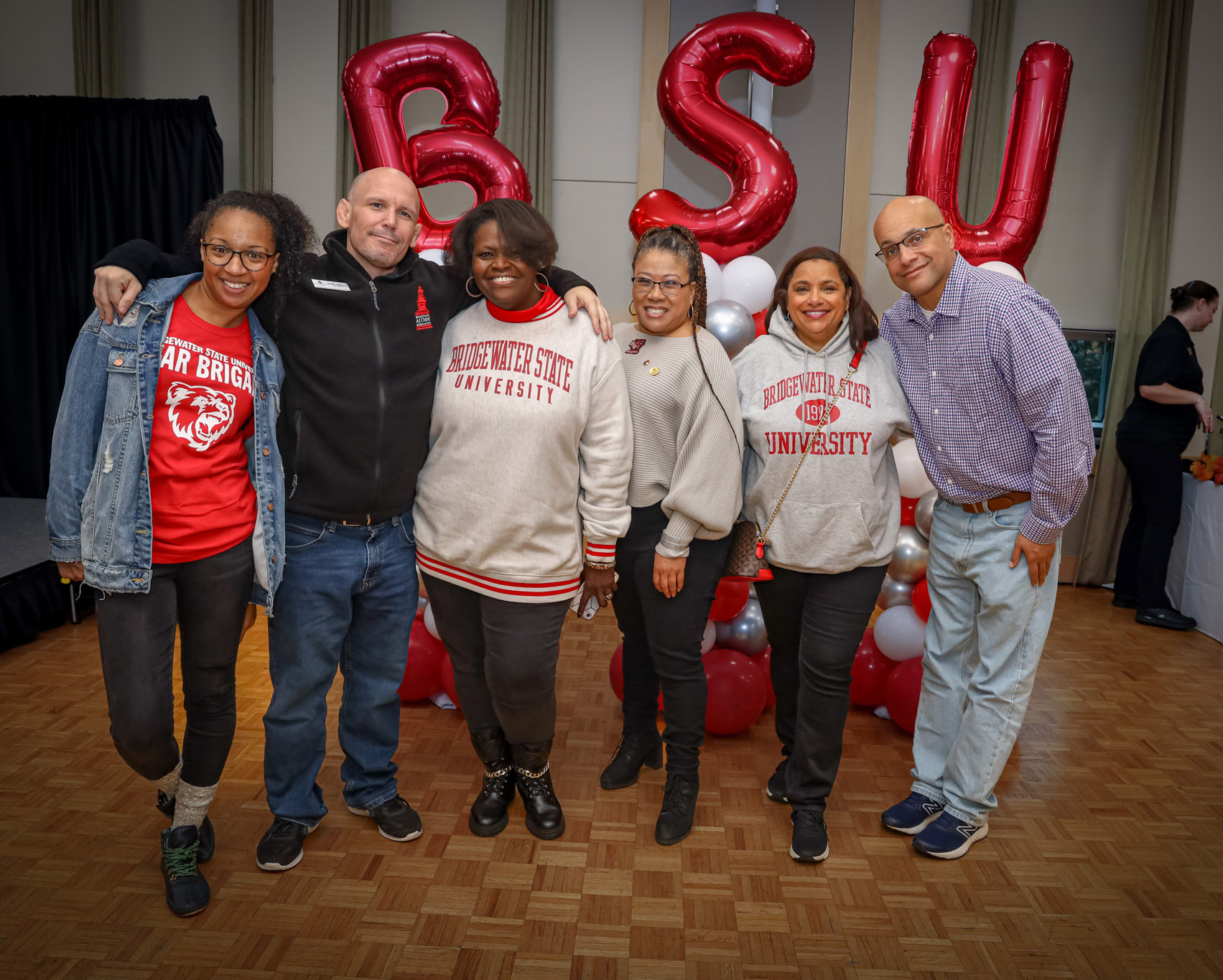 Six BSU alumni stand smiling in front of 3 large balloons spelling out BSU