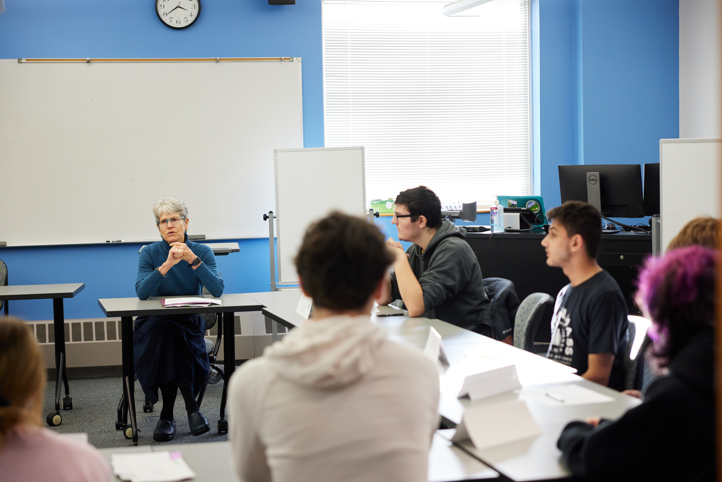 Dr. Susan Eliason teaches an Elementary Education class. She and the students sit at desks set up in a hollow square.