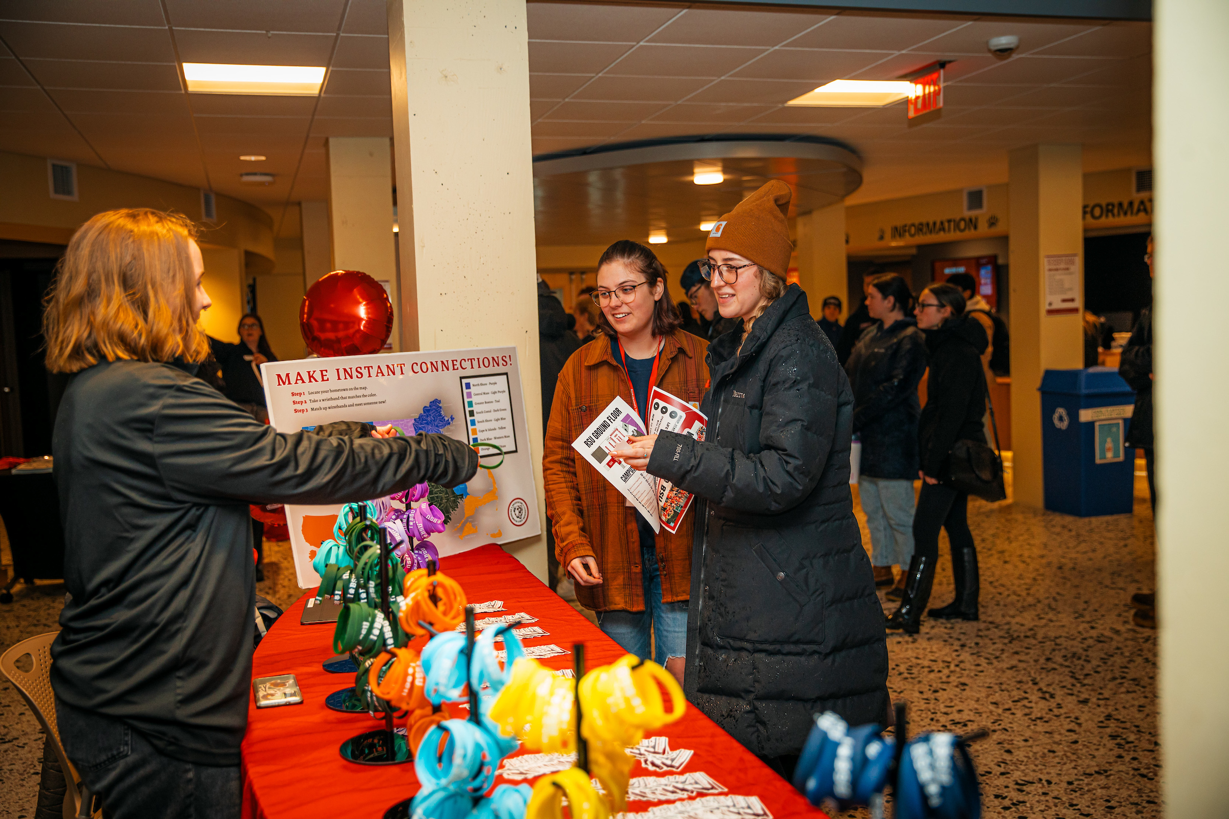 2 transfer students talk to another student behind a table with a sign that says Make