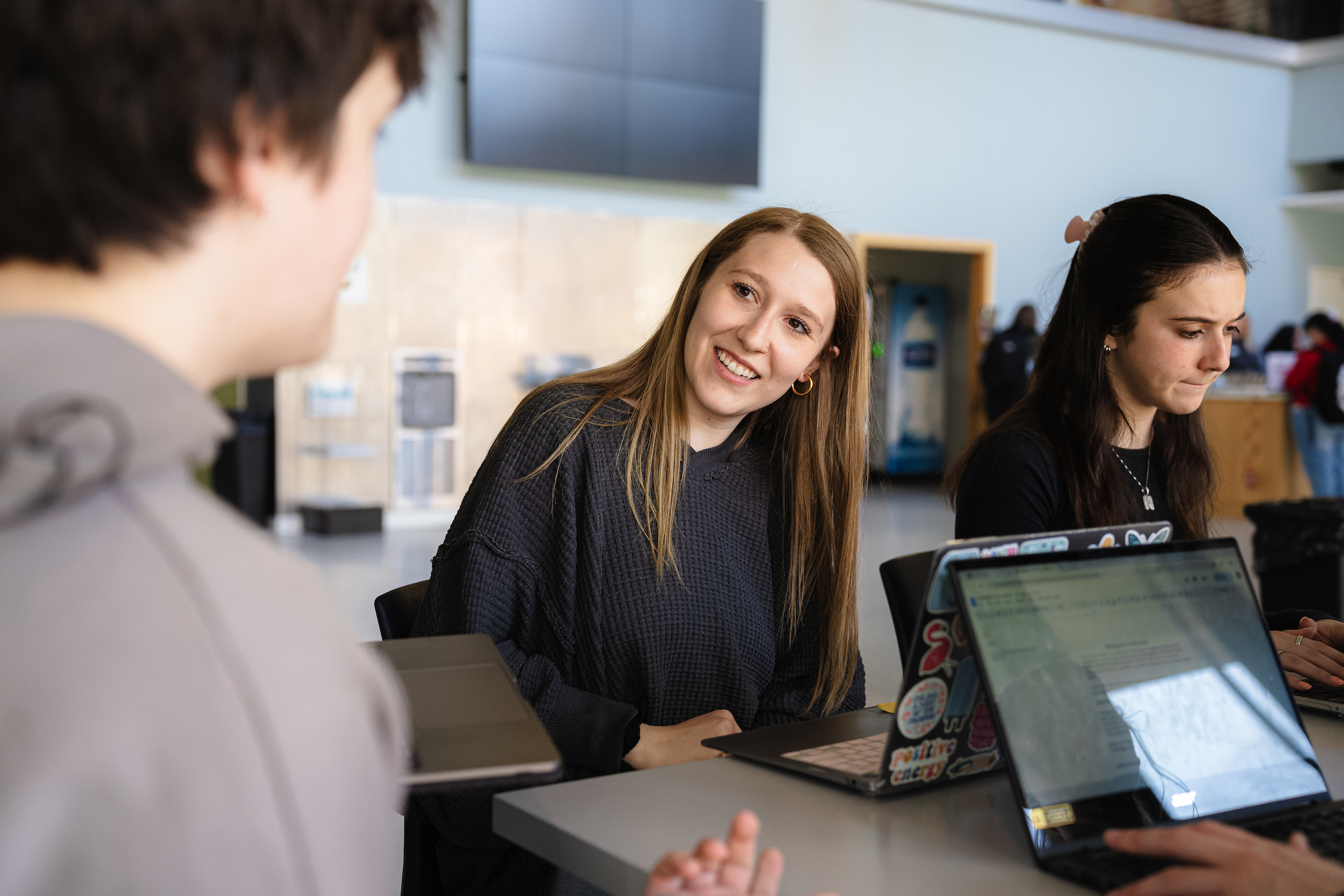 Four BSU students work and talk together at open laptops