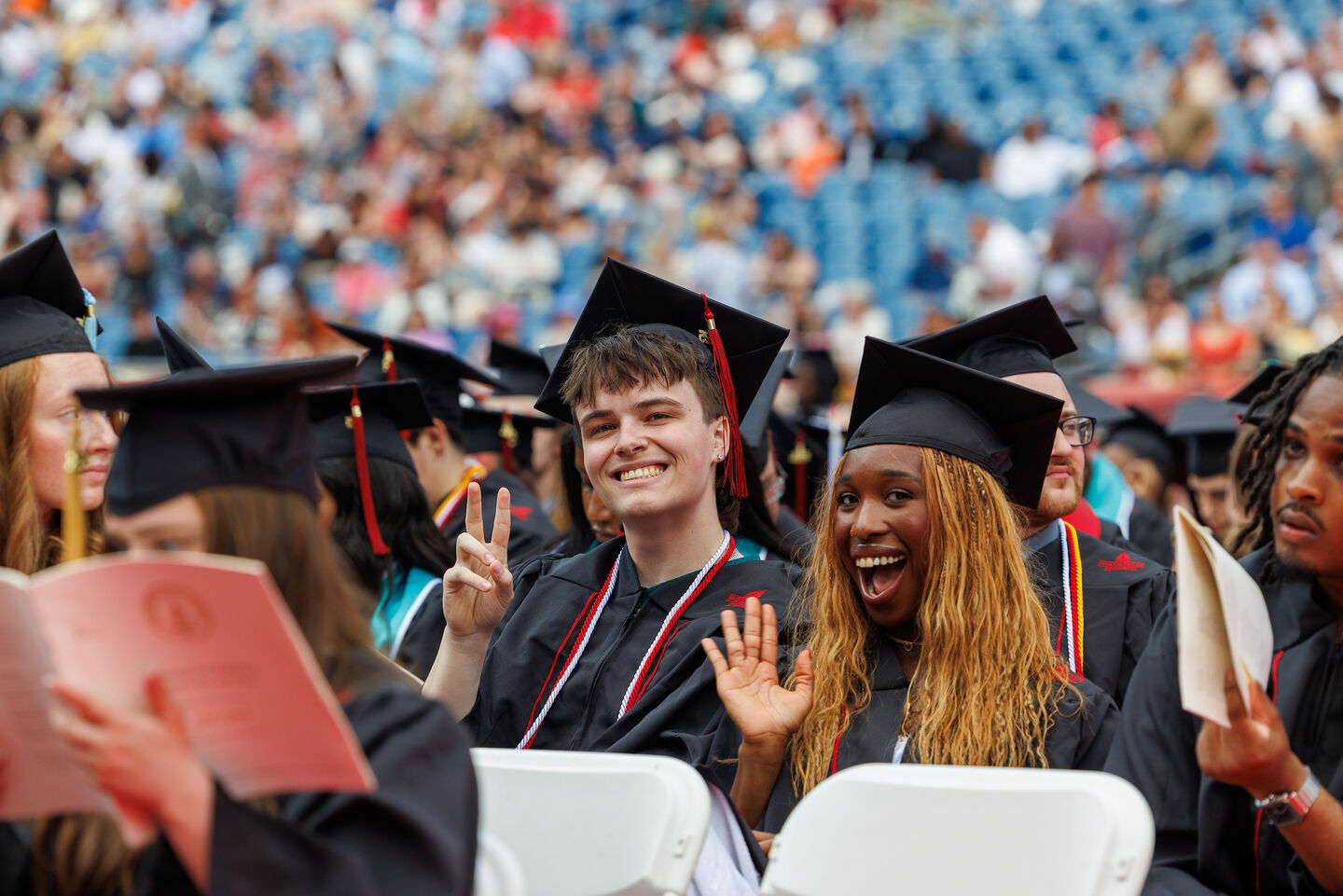 undergraduate commencement students wave to the camera