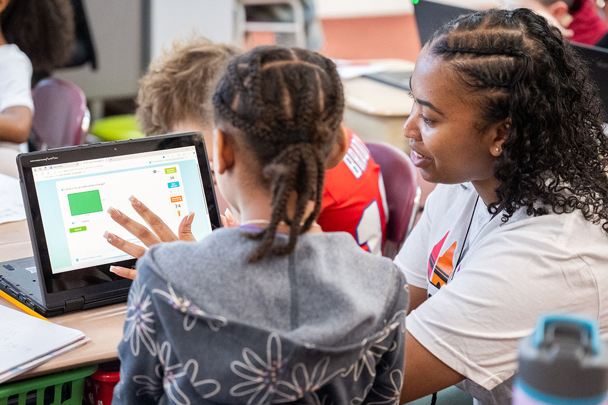 A BSU student teacher helps an elementary school student with work on a laptop