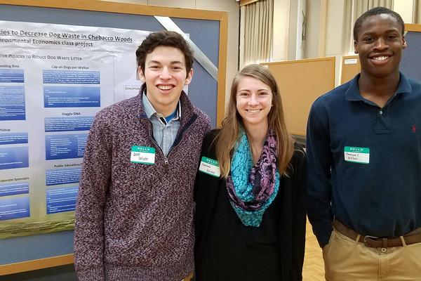 students smiling in front of their environmental symposium project