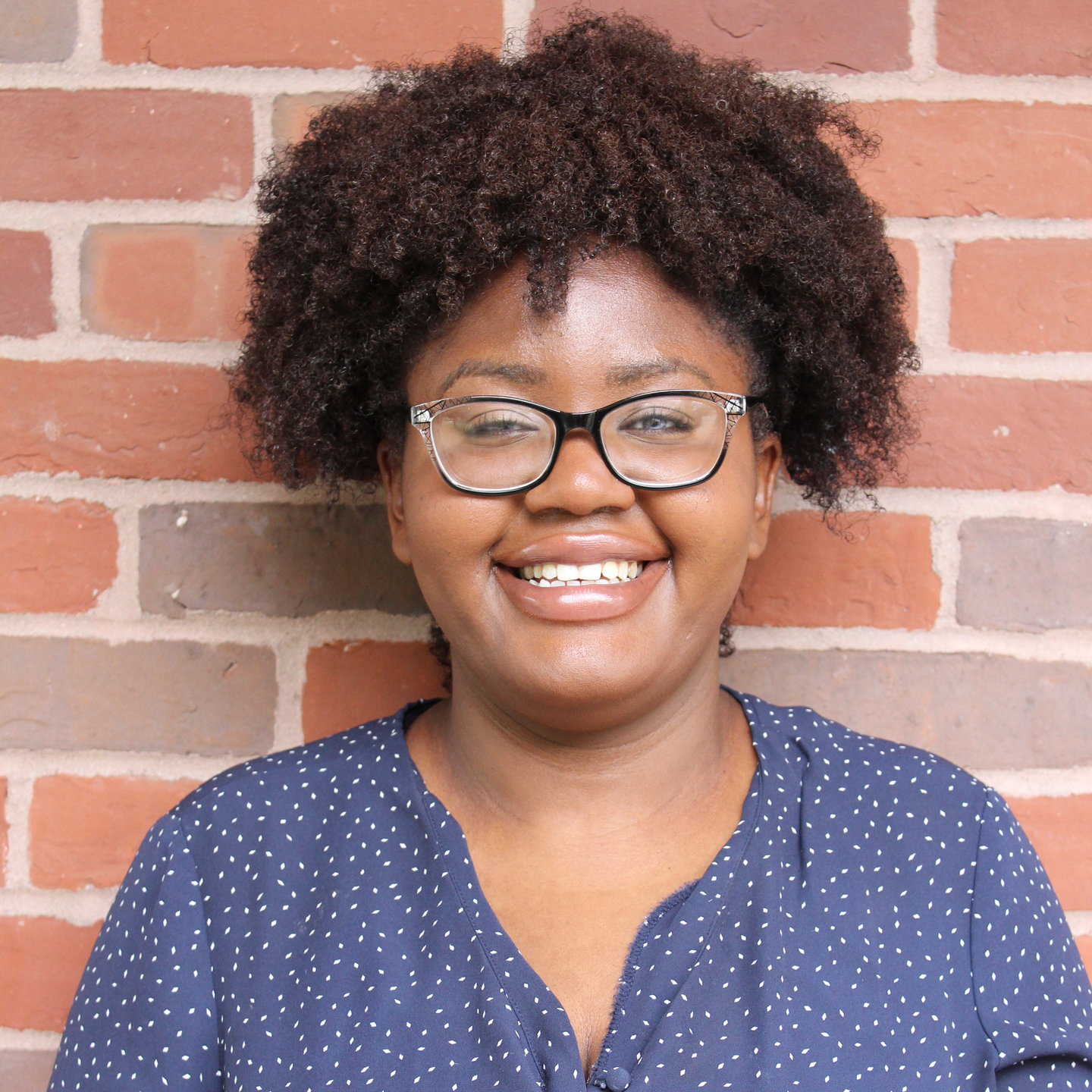 Photo of female student with glasses smiling at the camera