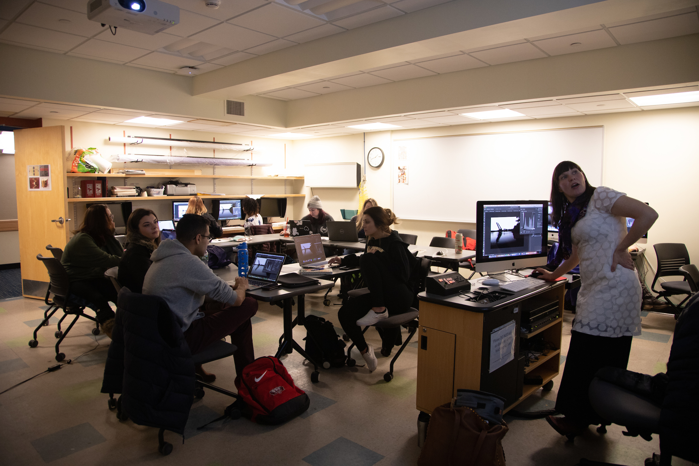 Professor Amy Lovera showing and talking about a photo on a screen while students follow along on their laptops