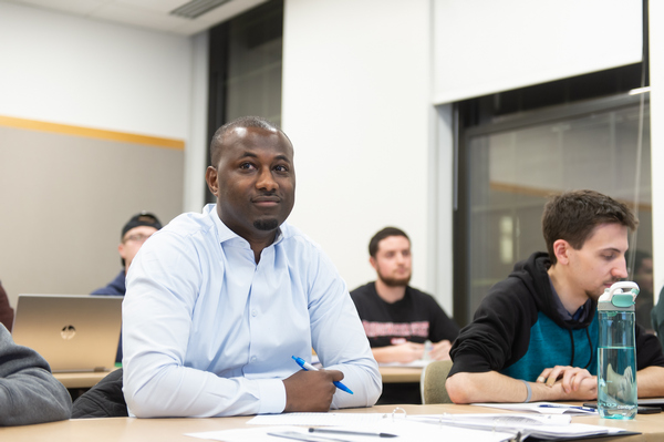 4 students sitting at desks in in a graduate class