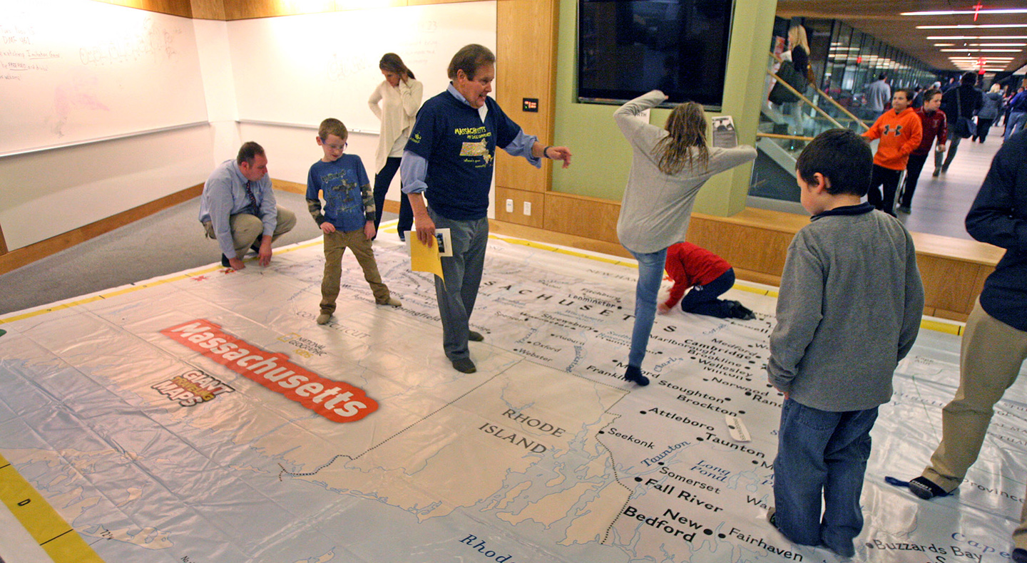 Children checking out the floor map of Massachusetts with Professor Domingo