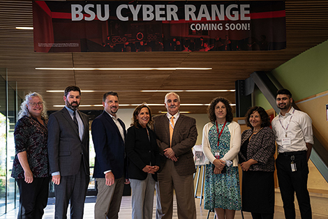 BSU, state and federal cybersecurity experts gather under a sign announcing BSU's new cyber range