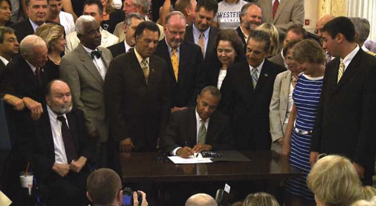 Governor Deval Patrick surrounded by BSU community members, signing legislation to grant university status