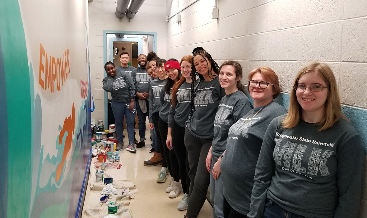 A group of students pose with a wall they painted for MLK day of service