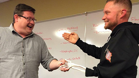 Greg Reynolds shakes hands with a professor using his skeleton arm.