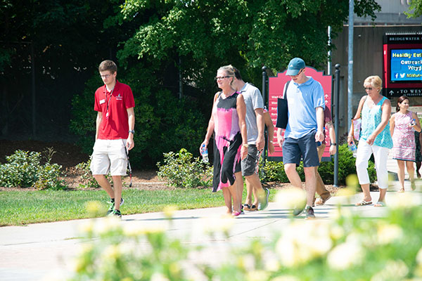 saturday_tours_cta.jpg a male student in a red BSU shirt leading a small group of prospective students and parents on a campus tour