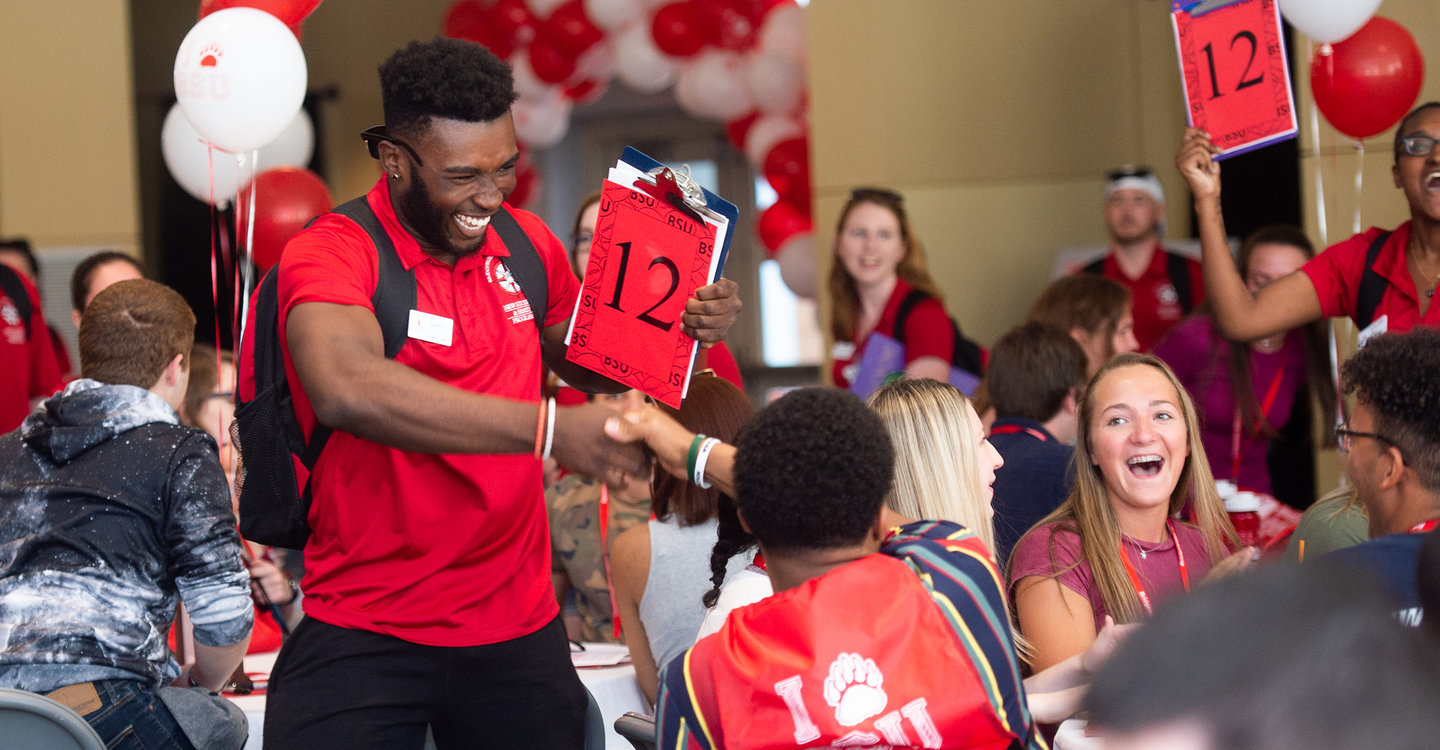 An orientation leader shaking hands with a new student