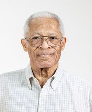 BSU Board of Trustees member Francis Giles with short gray hair and silver rimmed glasses. He is wearing a white button down collared shirt with thin colored horizontal and vertical lines.