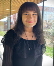 BSU Student Trustee Avery Barry smiling with long dark brown hair and wearing a black top with a lace ruffle