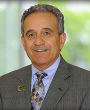 Dr. Robert Antonucci with short gray hair wearing a gray blazer over a light blue button down shirt and gray and blue tie