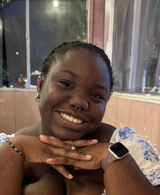 Cynthia Esterlin smiling with short braided black hair wearing a white with blue print top