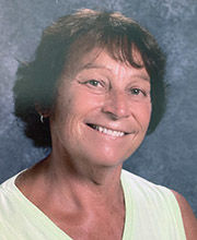 headshot photo of Elaine Clement-Holbrook with short wavy brown hair wearing a v-neck sleeveless off-white top