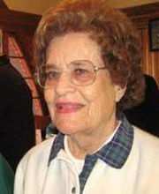 headshot of Hazel Varella with short curly brown hair wearing glasses and a white top with blue plaid collar