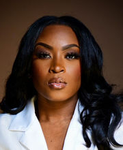 Joanna Edwards with long black wavy hair and wearing a white collared blazer