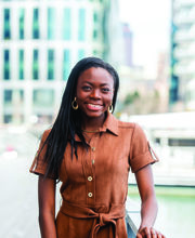 Keyana Adarkwah smiling with long straight black hair wearing a brown dress with Boston buildings in background