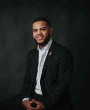 Luis Pires smiling with short black hair, mustache and beard and wearing a black blazer over a white button up shirt