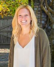 Dr. Amy Mercado smiling with long blonde hair and wearing a v-neck white blouse under an open taupe sweater