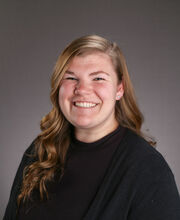 Tori Field smiling with long wavy dirty blonde hair and wearing a black top